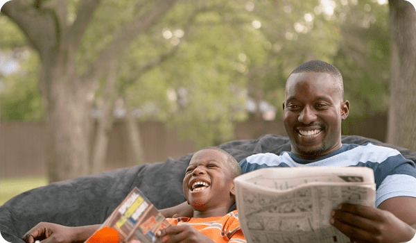 Middle aged dad sitting with son reading paper learning about Christian financial planning thinking to himself, Am I  being good enough steward or are some of my stocks chasing mammon or money? Starting to consider Biblically Responsible Investing.