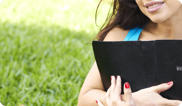 Girl holding her Bible in an outdoor setting.