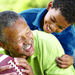 African American grandfather playing football with his grandson. He's answered the call to action by investing wisely in faith based mutual funds. 